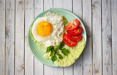 fried egg with tomatoes and parsley on wooden background