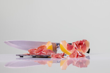 cured ham slices on a dark plate next to a melon slice with cured ham slices on top