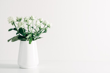 Home interior floral decor. Beautiful flowers white roses in vase on white background.