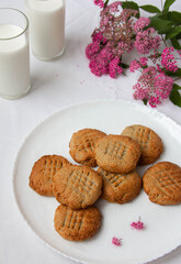 homemade peanut cookies with milk and pink flowers on the white background