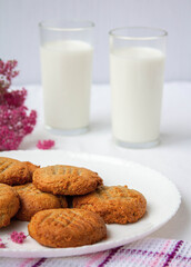 homemade peanut cookies with milk and pink flowers on the white background