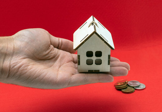 Buying a new home and housing, concept. A small model of a wooden house with a toy shopping cart.