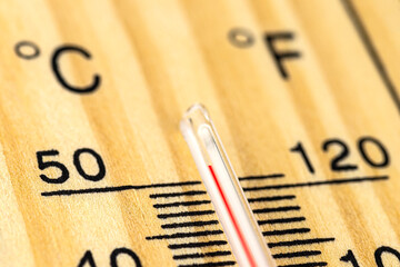 .A macro shot of a classic wooden thermometer showing a temperature over 50 degrees Celsius, 122 degrees Fahrenheit.