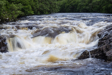 Long exposure shot of the waterfalls in Glen Orchy near Bridge of Orchy in the Argyll region of the highlands of Scotland during summer whilst the river is flowing fast from rainfall