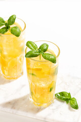 Citrus lemonade or mojito cocktail with lemon and orange and basil. Cold beverage or drink with ice on marble cutting board