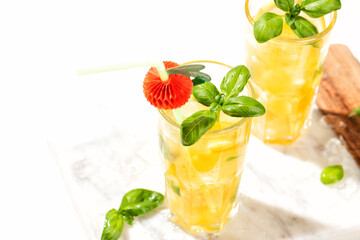 Citrus lemonade or mojito cocktail with lemon and orange and basil. Cold beverage or drink with ice on marble cutting board