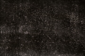Grunge surface texture with splashes, dots, grit and noise. A texture with random gray dots on a black background, similar to the starry sky, space.