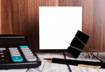 Calculator, pen and white sheet on a wooden table. A place to insert text. Business concept