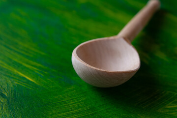 Empty wooden spoon on color painted background, close up