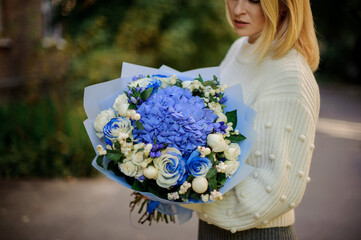 Close-up of bouquet with blue and white flowers in the hands of woman.