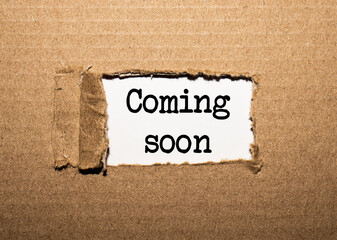 The text COMING SOON. behind torn brown paper