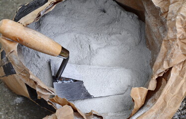 Close up trowel and cement powder in paper bag.