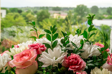 Bouquet of flowers in a box given to any wife for the anniversary. Bunch of flowers with roses, daisies and greenery on a window background. Close up.