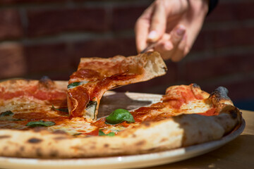 American pizza with pepperoni, mozzarella and tomato sauce. Pizza on a wooden table, morning, dawn.