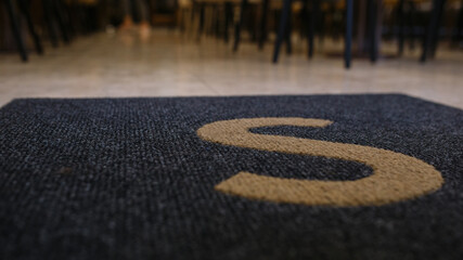 mat at the entrance to the restaurant. Uppercase S