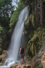 Hombre de espaldas mirando una cascada