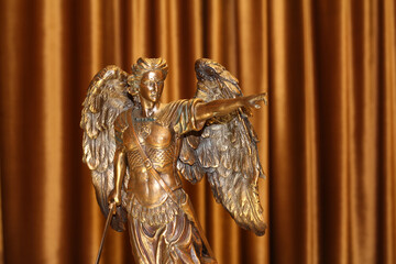 A bronze statuette of the Archangel Michael points a finger forward.