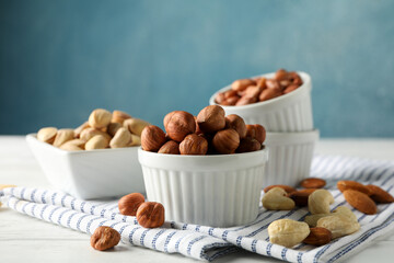 Bowls with different nuts on white wooden background. Vitamin food
