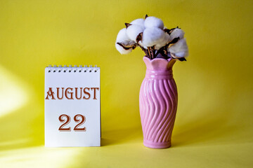 Calendar with text 22 august on yellow background and with a vase of flowers