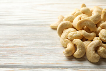Tasty cashew nuts on white wooden background. Vitamin food