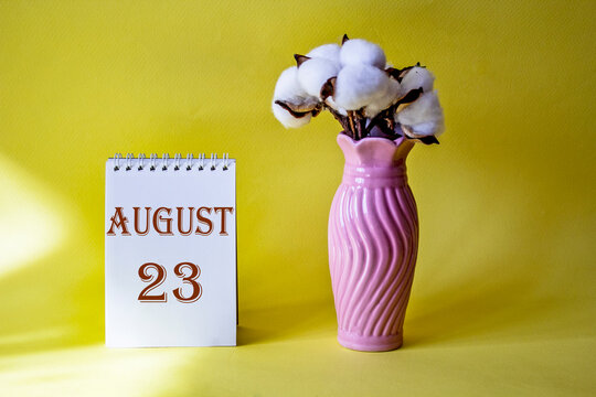 Calendar with text 23 august on yellow background and with a vase of flowers