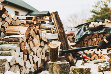 Close up of black axe splitting wood. Man cutting wood logs for firewood. Lumberjack at work, wood piles and sawdust on ground