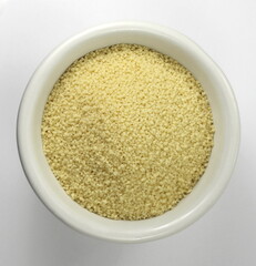 Dry couscous in white ceramic bowl isolated on white. 