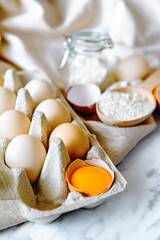 Baking ingredients with eggs, wheat flour, egg yolks for pastry. Cake, pasta or dough recipe ingredients. Top view on table