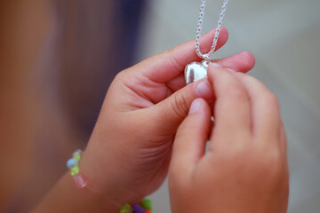 Children's hands holding a beautiful chain with a pendant so close
