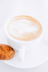 White coffee cup with a single cookie