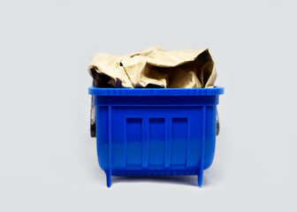 Blue plastic toy garbage waste can bin container full with paper cartboard carton rubbish at...