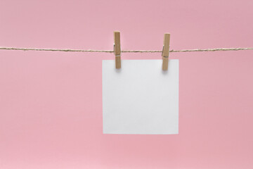 Close-up Of Blank Notes Hanging On Rope Against Pink Background