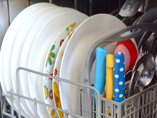 Open dishwasher with clean dishes, close up. Dishwasher after cleaning process.
