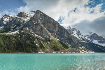 LAKE LOUISE, AB, CANADA - JUNE 2018: Emerald waters of Lake Louise in Banff National Park, surounded by snow capped mountains.