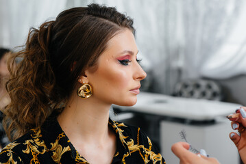 In a beautiful, modern beauty salon, a professional makeup stylist makes makeup for a young girl....