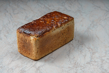 rectangular loaf of wheat bread with a baked shiny crust on the kitchen table.
