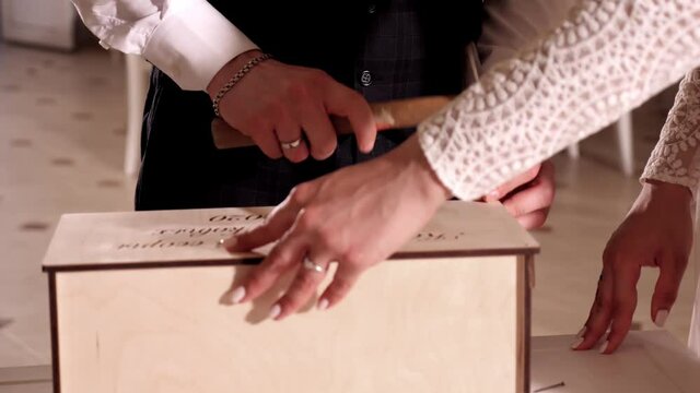 Newlyweds hammer nails closing a ritual wooden box. Holiday and good mood. Family