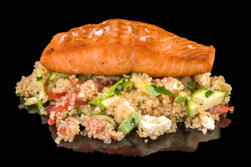 A delicious salad with a salmon fillet with quinoa with reflection, isolated on black background