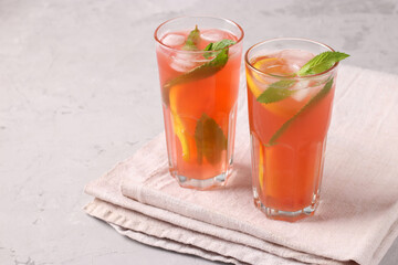 Healthy vitamin rhubarb and strawberry summer drink with mint, lemon and ice on a light gray concrete table, horizontal format, Copy space