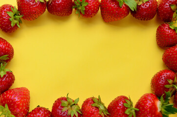 Strawberry red ripe sweet is laid out in a circle frame as a frame on a yellow background view from above with a copy space