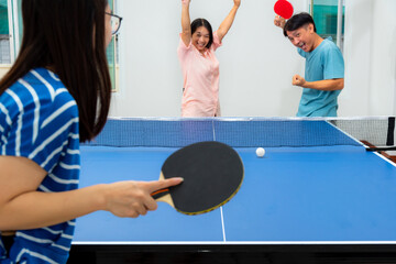 Couple fun playing table tennis or Ping pong indoor together leisure with competing in sports games at house. Father mother and daughter Asian family enjoy recreation exercise stay at home in Thailand - obrazy, fototapety, plakaty