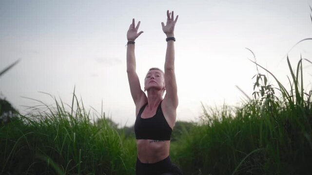 Young woman practice yoga outdoor in rice fields in the evening during wellness retreat in Bali. Slow Motion Rapid