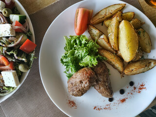 Home-style cutlets on a white plate with baked potato peasant