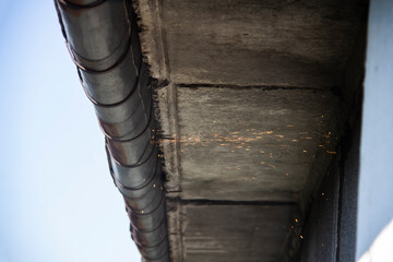 Obraz premium Replacement gutter system with Welding machine for a metal roof. Holder gutter drainage system on the roof. Cut off a gutter system on the roof.