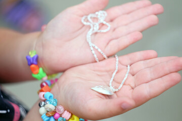 Children's hands holding a beautiful chain with a pendant so close