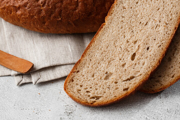 Close-up of homemade bread. Peasant round bread and wheat spikelets with space for text. Homemade baking. Sliced brown bread with sour cream on wooden chopping board wheat rye ears copy space.