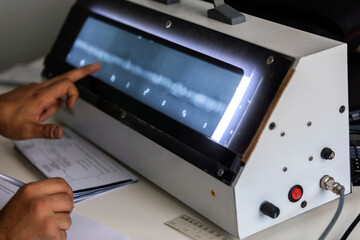 The inspector evaluation radiography of the weld metal with X-Ray film viewer box. He write some...