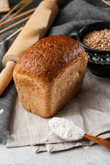 Close-up of homemade bread. Peasant square bread and wheat spikelets with space for text. Homemade baking. Gray bread with flour on wooden chopping board wheat rye ears copy space.