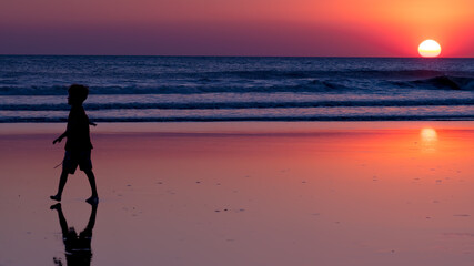 a child plays on the beach, backlight and sunset. 