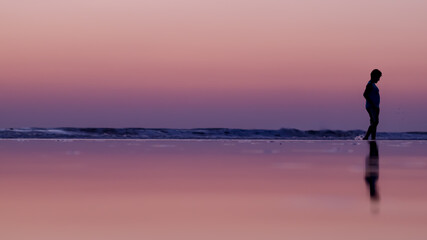 Sadness of a child on the beach, sunset, shadows.